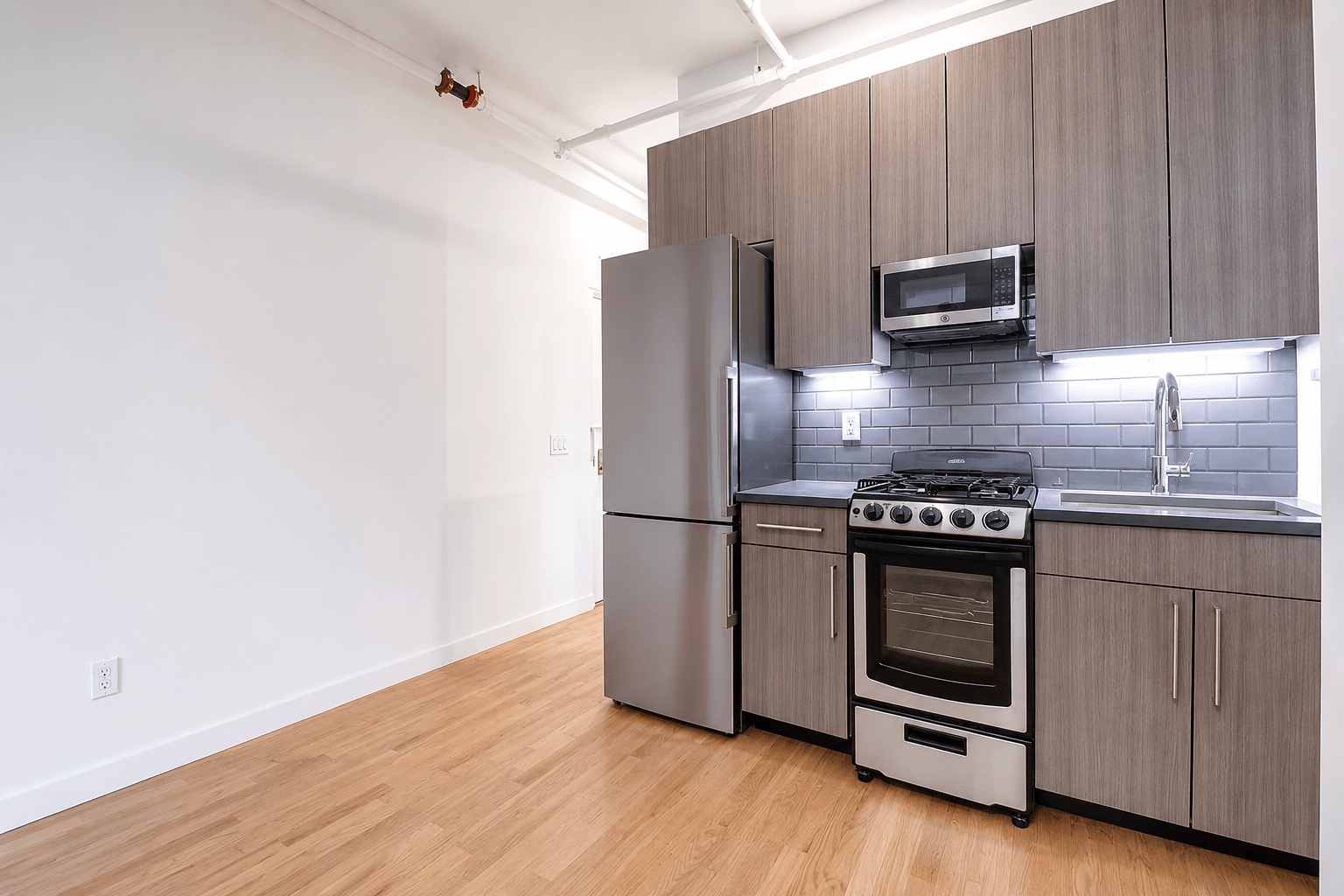 A kitchen with a stove, refrigerator, and microwave.